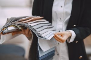 Produção Têxtil: Mulher com roupa corporativa segurando uma amostra de tecidos